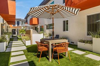 A backyard patio with a table and chairs under an umbrella